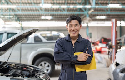 mechanic smiling by a car in an Omaha auto repair shop